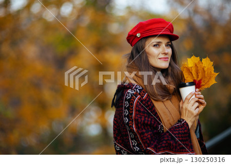pensive modern woman in red hat with autumn leafs pensive modern woman in red hat with autumn leafs 130250316