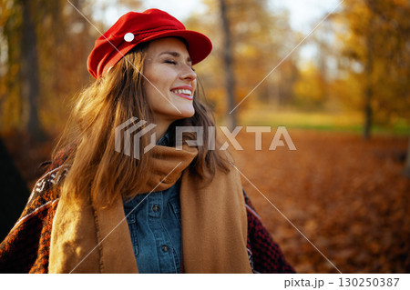 smiling modern female in red hat with scarf in city park smiling modern female in red hat with scarf in city park 130250387