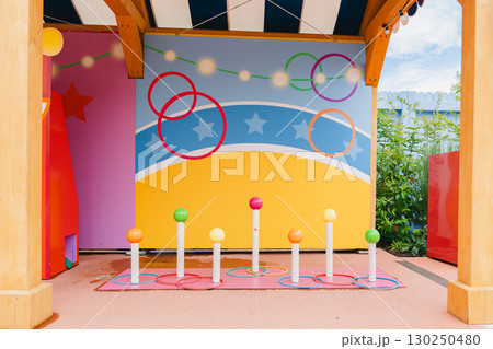 Colorful ring toss setup in a playful outdoor setting features vibrant poles and a cheerful backdrop. Perfect for family fun, carnival events, or enhancing play areas. 130250480