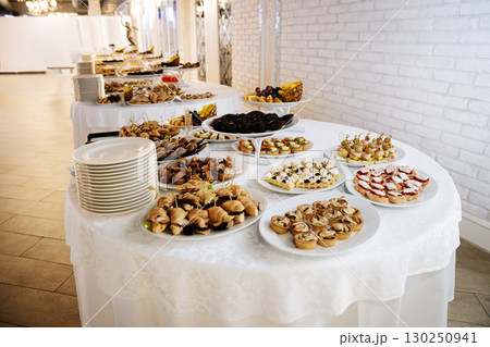 Elegant buffet table with gourmet canapes, desserts and fruit at festive banquet event 130250941