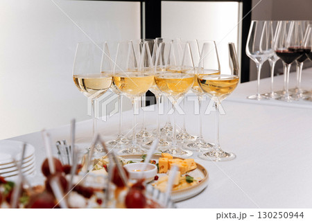 Elegant white wine glasses and gourmet appetizers at a modern event reception 130250944