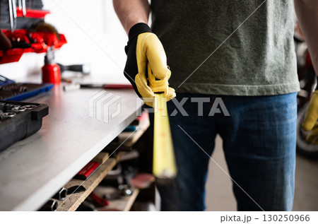Auto Mechanic Holds A Measuring Tape In The Garage 130250966