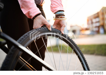 Girl Checking Bike Tire Pressure On A City Street 130251033