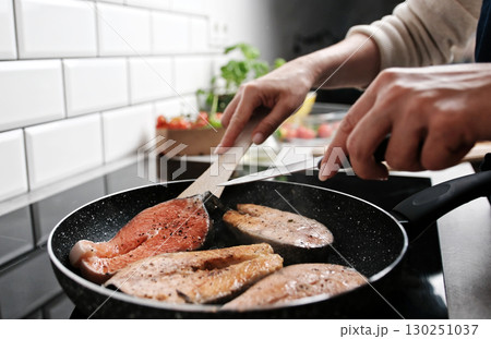 Girl Frying Red Fish Salmon In A Pan On The Kitchen Stove Cooking Healthy Dinner At Home Girl Frying Red Fish Salmon In A Pan On The Kitchen Stove Cooking Healthy Dinner At Home 130251037