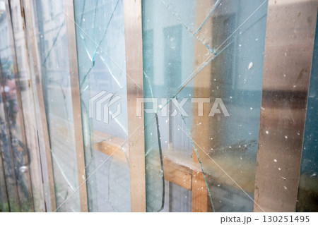 Old broken glass with big and little cracks in close building. Dirty window with protection and view of the city street. 130251495