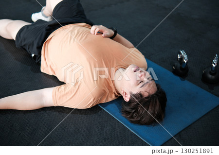 Exhausted man collapsed and lying on the floor after a hard workout. 130251891