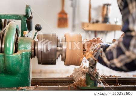 Carpentry. Turnery of a wooden bowl with spiral sawdust shavings with hand and chisel Carpentry. Turnery of a wooden bowl with spiral sawdust shavings with hand and chisel 130252606