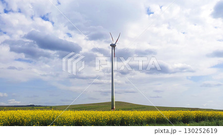 Big white windmillon the nature background with green field and blue sky. Wind turbine for alternative green energy in Europe. Big white windmillon the nature background with green field and blue sky. Wind turbine for alternative green energy in Europe. 130252619