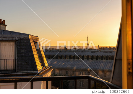 Stunning view from the window of the Eiffel Tower and roofs of houses at golden hour Stunning view from the window of the Eiffel Tower and roofs of houses at golden hour 130252665
