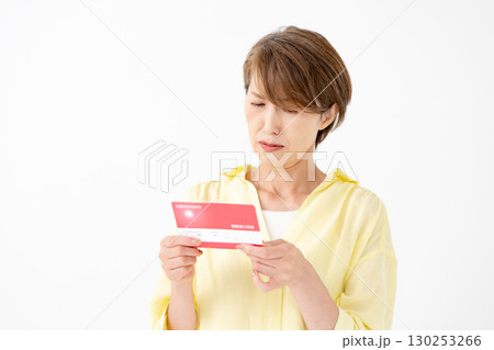 通帳を見て悩むミドル女性　 130253266