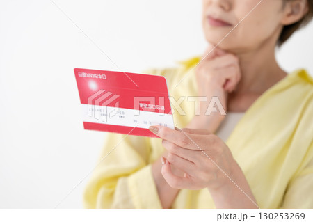 通帳を見て悩むミドル女性　手元 130253269