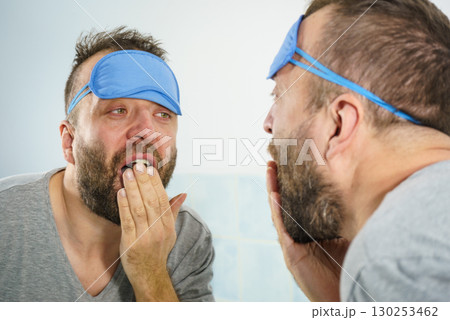 Sleepy man looking at mirror and yawning Sleepy man looking at mirror and yawning 130253462