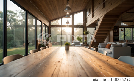 Modern wooden dining room with large windows showcasing natural light and green landscape view 130255257