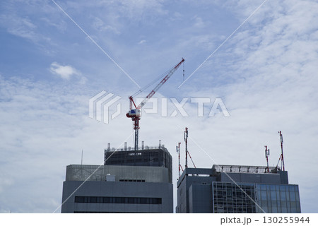 工事中のビルがあります。クレーン車が屋上にあります。 130255944