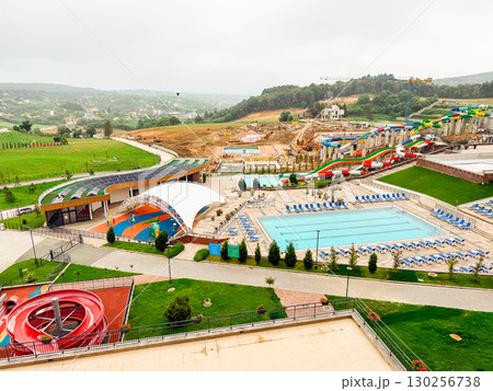 Waterpark with pools, colorful slides, and sunbeds surrounded by hills and countryside landscape. Tourism, leisure, and recreation symbolizing summer activity, entertainment, and vacation lifestyle. 130256738