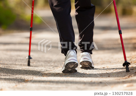 Nordic walking. Female legs hiking in the park. Nordic walking. Female legs hiking in the park. 130257028