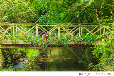 Old small bridge over river in green garden. Old small bridge over river in green garden. 130257060