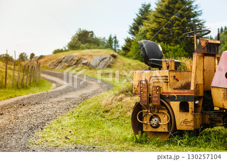 Combine harvester standing next to coutryside path 130257104