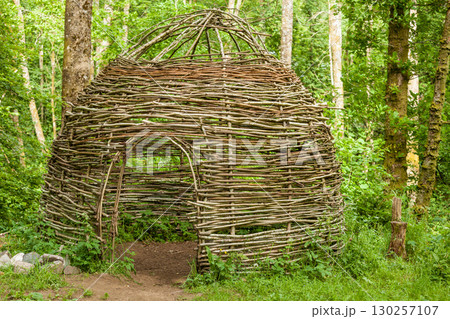 Small cottage made of wooden sticks in woods 130257107