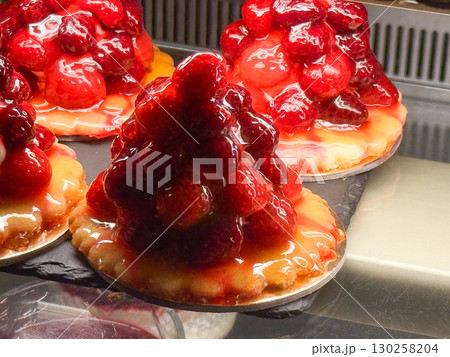 Mini fruit tarts with cream and fresh berries. Colorful confectionery, sweet dessert and gourmet patisserie display. 130258204