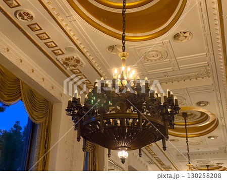 Ornate chandelier and golden ceiling in luxury hotel. Classic architecture, intricate details and elegant evening interior. 130258208