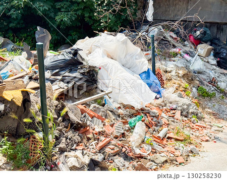 Pile of garbage and plastic waste among green grass. Pollution, environmental damage, and ecological issues in urban surroundings. 130258230