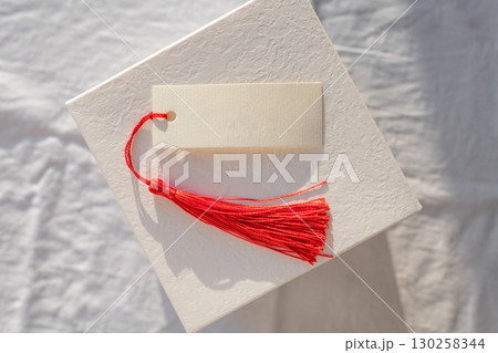 Blank card with Red Tassel Displayed on white gift box Blank card with Red Tassel Displayed on white gift box 130258344