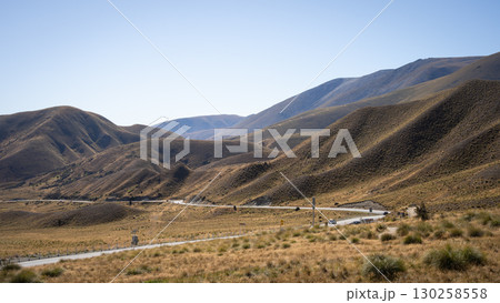Highway running through hilly valley with no trees, Lindis Pass, New Zealand 130258558