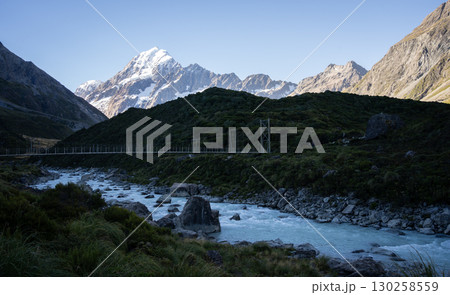 Beautiful alpine valley with glacial river, swing bridge and snowy mountain, Mt Cook, New Zealand 130258559