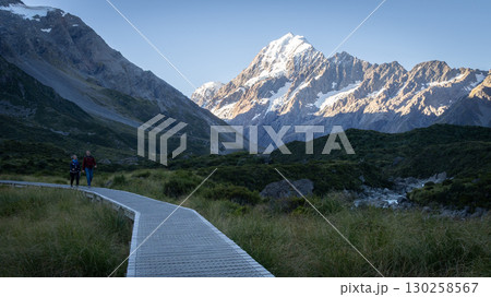Happy couple walking on a trail with snowy mountain in backdrop, Mt Cook, New Zealand 130258567