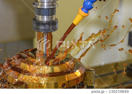 Close up scene the CNC milling machine finishing cut the brass shell mold parts with oil coolant method. Close up scene the CNC milling machine finishing cut the brass shell mold parts with oil coolant method. 130259689
