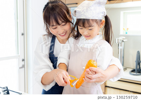 人参の皮剥きをする小学生の女の子とお母さん 130259710