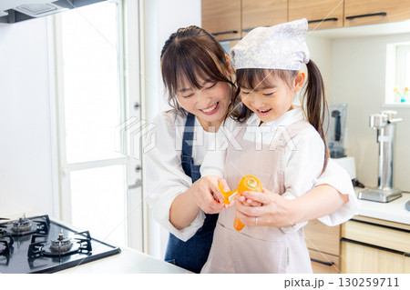 人参の皮剥きをする小学生の女の子とお母さん 130259711