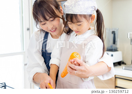 人参の皮剥きをする小学生の女の子とお母さん 人参の皮剥きをする小学生の女の子とお母さん 130259712