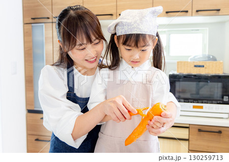 人参の皮剥きをする小学生の女の子とお母さん 130259713