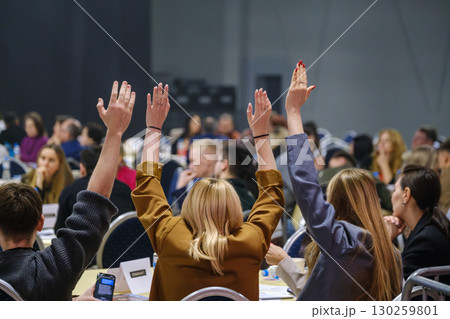 Group of people voting with raised hands in a lively conference 130259801