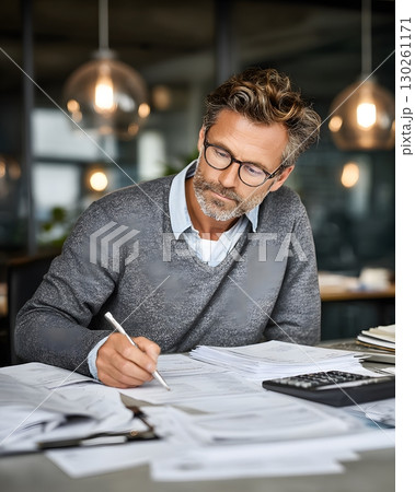 man analyzing tax reports with pen and calculator in modern workspace 130261171