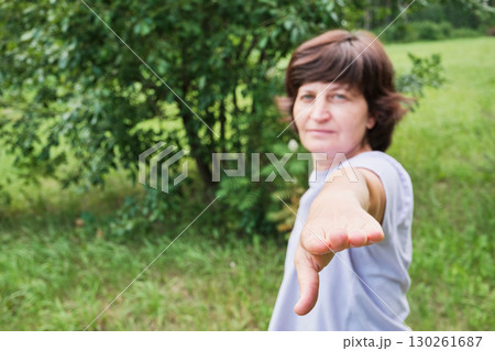 Mature woman doing pilates at public park, focus on hand. Healthy lifestyle Mature woman doing pilates at public park, focus on hand. Healthy lifestyle 130261687