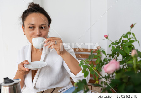 Woman Enjoying Coffee Outdoors Near Flowering Plants in Relaxed Atmosphere 130262249