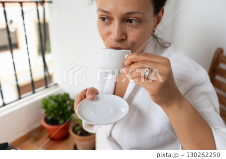 Woman Enjoying Relaxing Moment With Coffee on a Sunlit Balcony 130262250