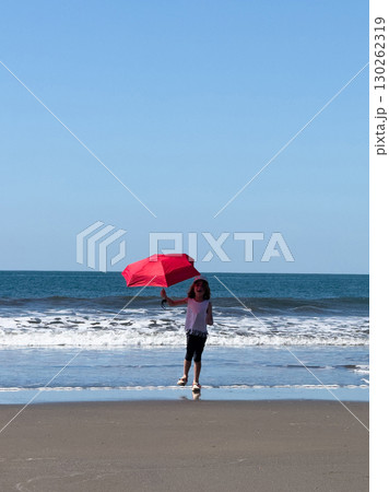 Kid run with red umbrella on beach 130262319