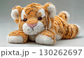Adorable, Soft Plush Stuffed Tiger Lying Down on the Floor Perfect for Cute Themed Projects, Boosting a Sense of Tranquility and Relaxation. 130262697