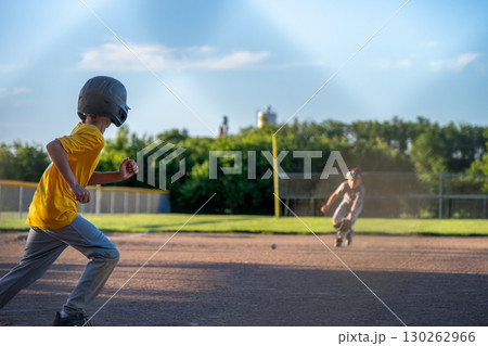 Kids playing baseball at a sunny field during late afternoon with focus on base running and catching Kids playing baseball at a sunny field during late afternoon with focus on base running and catching 130262966
