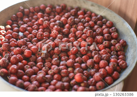 Large metal bowl filled with fresh red hawthorn berries for culinary use 130263386