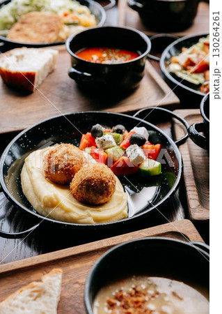 Delicious mashed potatoes with croquettes and fresh vegetable salad on rustic wooden table 130264261