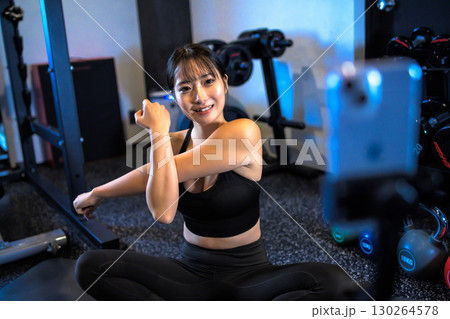 ジムで筋トレ動画配信をする20代女性 ストレッチ運動をするかっこいい女性 ライブ配信 ライバー ジムで筋トレ動画配信をする20代女性 ストレッチ運動をするかっこいい女性 ライブ配信 ライバー 130264578