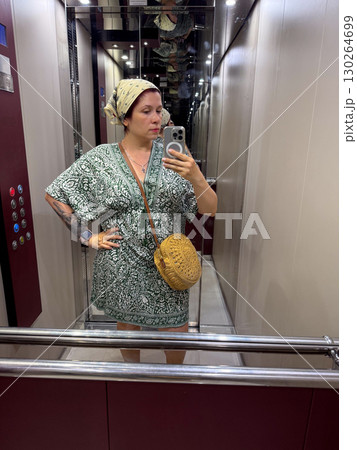 Woman taking a mirror selfie in an elevator. Fashion, lifestyle, and urban identity expression. Woman taking a mirror selfie in an elevator. Fashion, lifestyle, and urban identity expression. 130264699