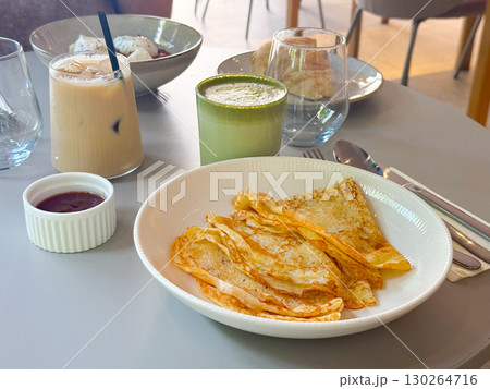 Thin pancakes served with sauce. Breakfast with iced coffee and matcha latte. 130264716