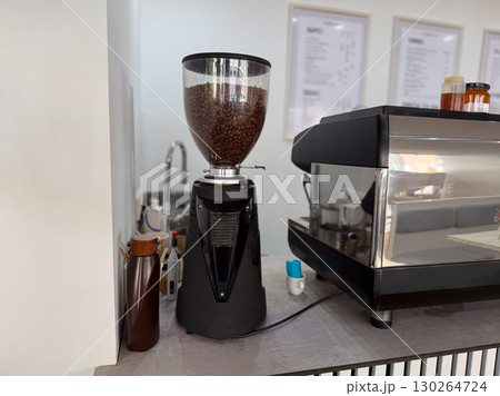 Coffee grinder filled with roasted beans. Fresh coffee preparation in a modern cafe. 130264724