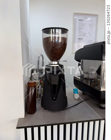 Coffee grinder filled with roasted beans. Fresh coffee preparation in a modern cafe. 130264725